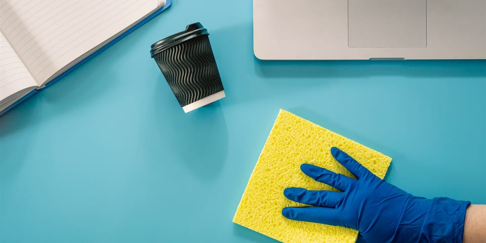 Professional cleaners washing windows and cleaning beneath furniture in a sunlit spring office
